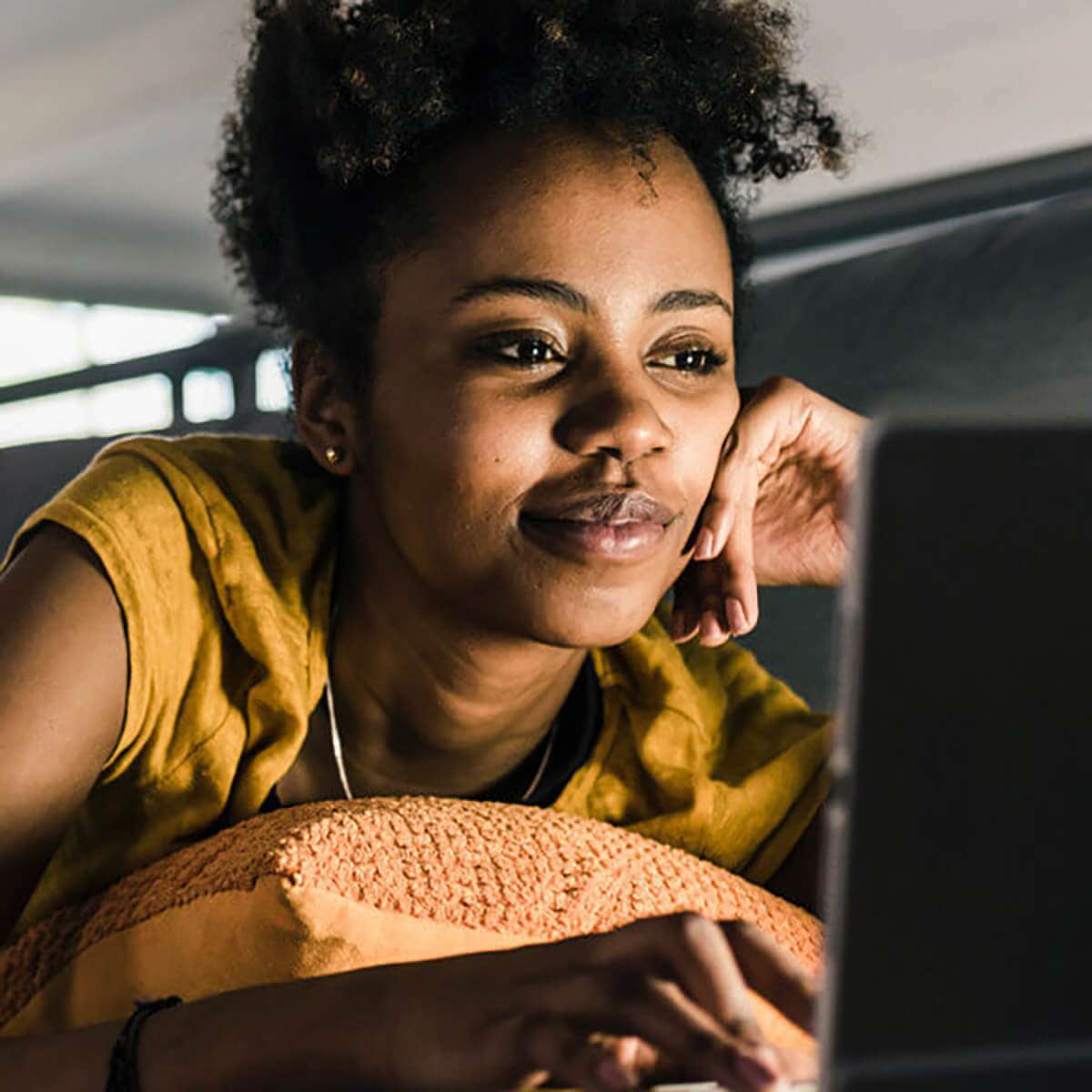 woman leaning on pillow using laptop