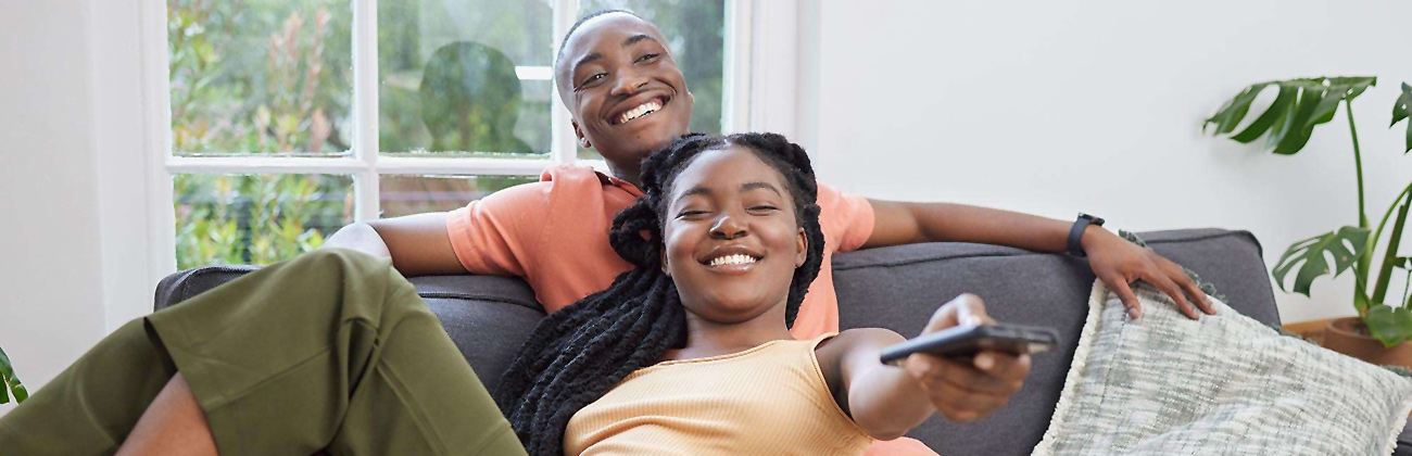 Couple on sofa watches TV with remote